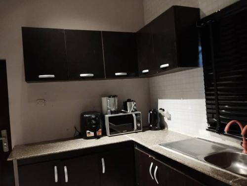 a kitchen with black cabinets and a counter top with a microwave at 1-3 Bedroom Luxury Oasis in PH City in Rumukoroshe