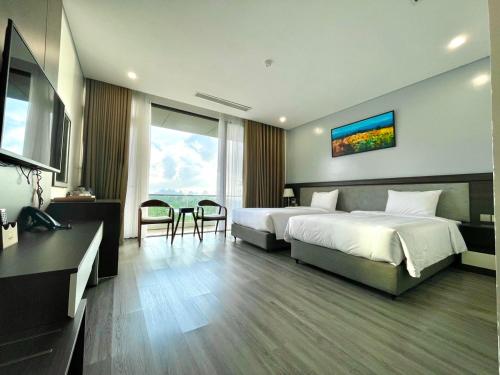 a hotel room with two beds and a table and a desk at DIAMOND HOTEL VÂN ĐỒN in Cẩm Phả