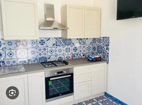 a kitchen with white cabinets and blue and white tiles at Villa Zaffiro in Isola di Lampedusa