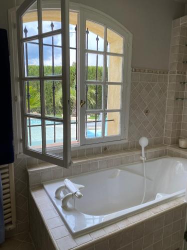 La salle de bains est pourvue d'une baignoire et d'une fenêtre. dans l'établissement Villa Rosana, 8p, large private pool, Frejus, à Fréjus