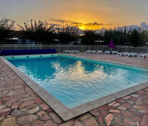 - une piscine avec des chaises et un coucher de soleil en arrière-plan dans l'établissement Casabella 3 chambres, à Cervione