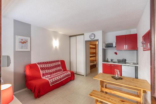 un salon avec un canapé rouge et une table dans l'établissement Cosy Marmottes - Au cœur du Parc National, à Barèges