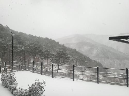 a fence covered in snow with mountains in the background at Daon Forest Pension in Inje