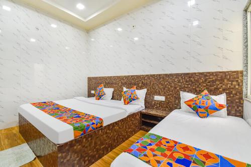 two beds in a room with white walls at FabHotel Maa Gayatri Sadan - Nr Pram Mandir Shree Banke Bihari Temple in Vrindāvan