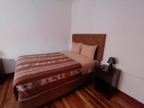 a bedroom with a bed and a lamp on a table at Magnolia Andina in Cusco