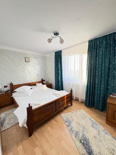 a bedroom with a large bed and green curtains at Pensiunea Angelica in Baia de Fier