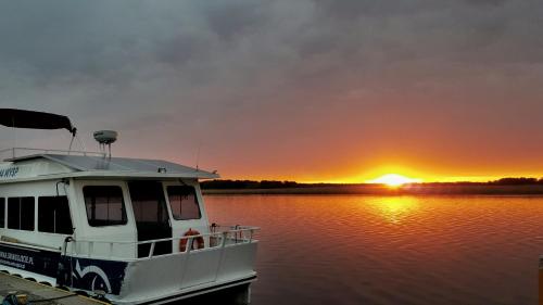 a boat docked at a dock with the sunset in the background at Karczma Rybna Rybaczówka Marina B&B in Świnoujście