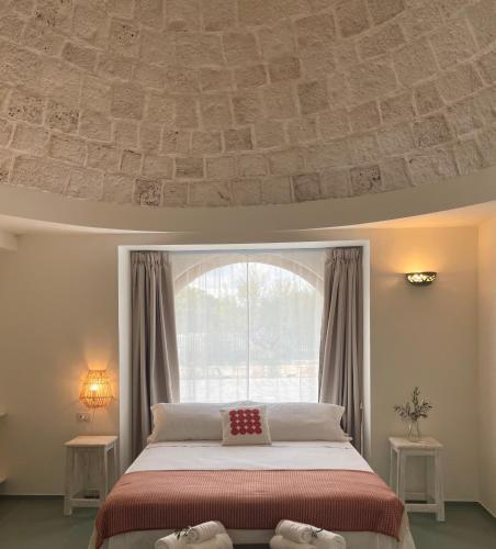 a bedroom with a bed and a large window at Trulli Milena in Putignano