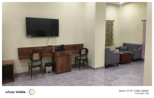 a room with two chairs and a television on a wall at The Grand Inn Resort in Dum Duma