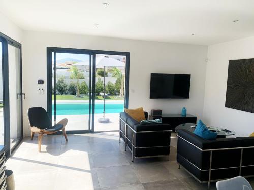 - un salon avec des canapés, une télévision et une piscine dans l'établissement Villa Plein Sud, à Villeneuve-de-la-Raho