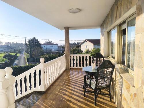 einen Balkon mit einem Tisch und Stühlen auf einem Haus in der Unterkunft Gran chalet con jardín, piscina y BBQ in Sada