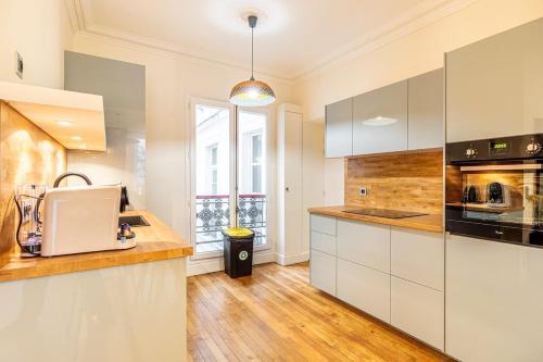 une cuisine avec des armoires blanches et un comptoir dans l'établissement Stay in the Heart of Le Marais!, à Paris