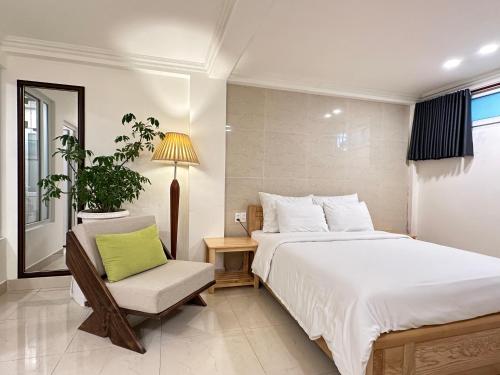 a bedroom with a large bed and a chair at CozyNook Boutique Apartments - 3 thang 2 Street in Da Lat