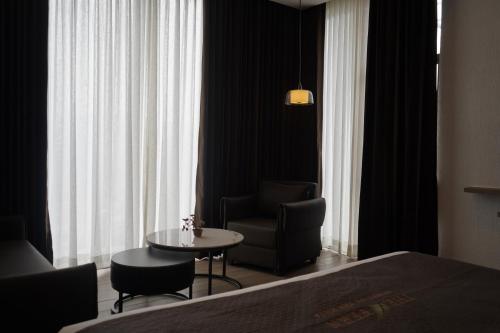 a room with a bed and a chair and a table at The Fern Heaven on The Hills Resort, Hatgad-Saputara in Surgāna