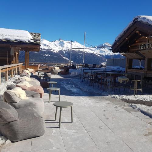 a patio with couches and tables and chairs in the snow at Thyon 4pièces, magnifique vue in Hérémence