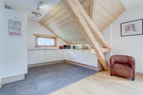 une cuisine mansardée avec des placards blancs et une chaise dans l'établissement Chanterelle apartement - Snow and Trek - Morzine, à Morzine