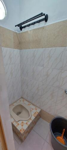 a bathroom with a toilet in a tiled floor at Villa Highland No 8 UU Berastagi View in Berastagi