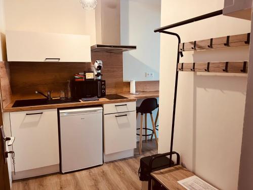 La cuisine est équipée de placards blancs et d'un four micro-ondes noir. dans l'établissement App du prince centre-ville Aurillac 2 pers, à Aurillac