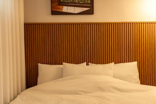 a bed with a wooden headboard and white sheets at Dal Stay in Seoul