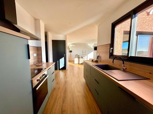 une grande cuisine avec un évier et une fenêtre dans l'établissement VillaPalmaé1, à Lapalme