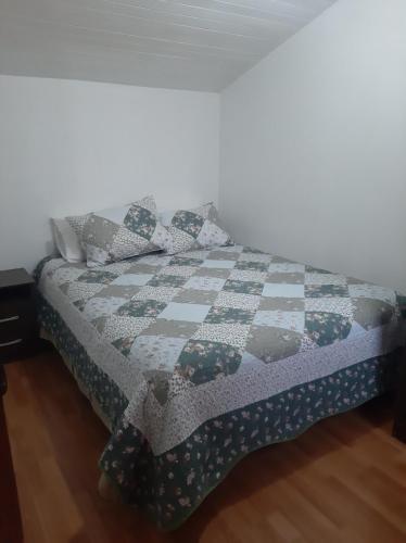 a bed with a quilt on it in a room at Cabaña para 2 personas en Valdivia in Valdivia