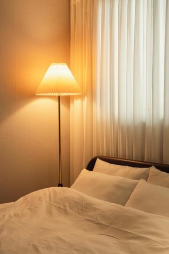 a bed with a lamp next to a window at Dal Stay in Seoul