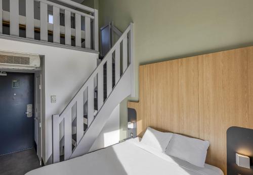 a bedroom with a bed and a stair case at B&B HOTEL Bordeaux Lac sur Bruges in Bruges
