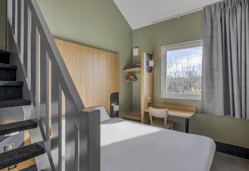 a small room with a bed and a staircase at B&B HOTEL Bordeaux Lac sur Bruges in Bruges