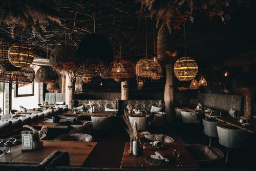 a restaurant with tables and chairs and chandeliers at Jufenalm BOHO & Wellnesshotel in Maria Alm am Steinernen Meer