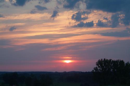 a sunset in the sky with clouds and trees at Fregata in Wilkasy