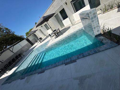a swimming pool in front of a house at Uniq suítes Japaratinga in Japaratinga
