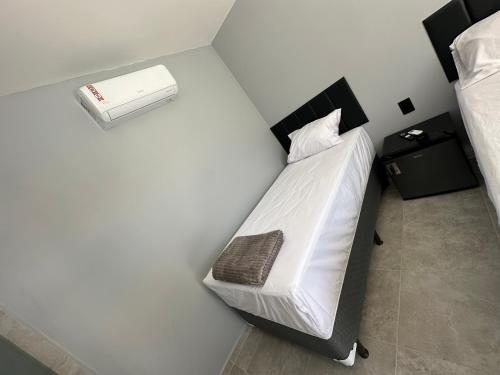 a bedroom with a white bed with a night stand at Uniq suítes Japaratinga in Japaratinga
