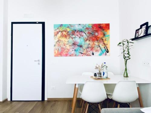 a dining room with a white table and a painting on the wall at M4 WHITE Monolocale Moderno e Funzionale in Scandicci