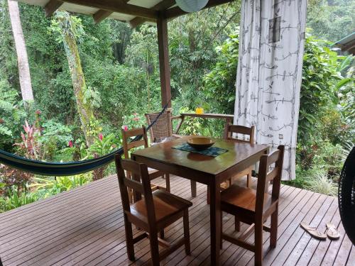 a wooden table and chairs on a deck with a hammock at Casa Lina sloth view exotic apartment with privat kitchen in Puerto Viejo