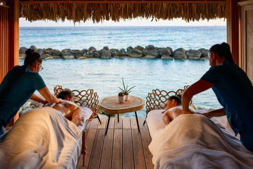 a group of people laying in beds on a deck looking at the ocean at Renaissance Wind Creek Aruba Resort in Oranjestad