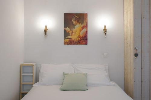 une chambre avec un lit blanc avec un tableau sur le mur dans l'établissement Maison au coeur du Marais - II, à Paris