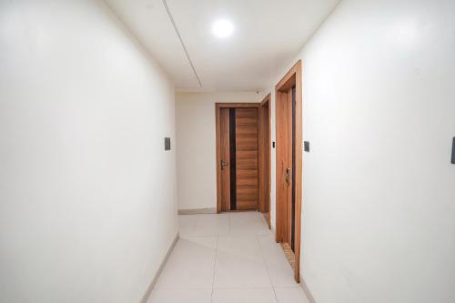 an empty corridor with a wooden door in a white room at FabHotel Shrinath Casa Inn in Bhopal