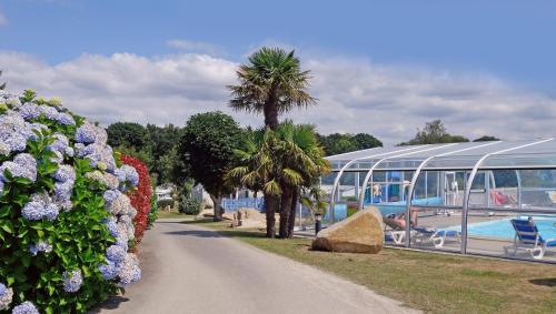 une passerelle à côté d'un bâtiment fleuri et d'une piscine dans l'établissement Domaine Résidentiel de Plein Air Kerleyou, à Douarnenez