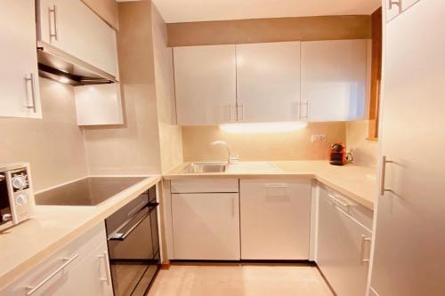 a kitchen with white cabinets and a sink at Mondzeu C261 in Bagnes