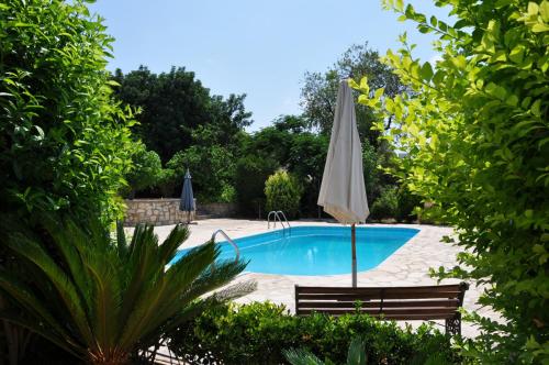 una piscina con sombrilla y banco en Anna Maria, en Peyia