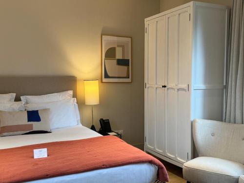 a bedroom with a bed and a chair at Les Manoirs des Portes de Deauville - Small Luxury Hotel Of The World in Deauville