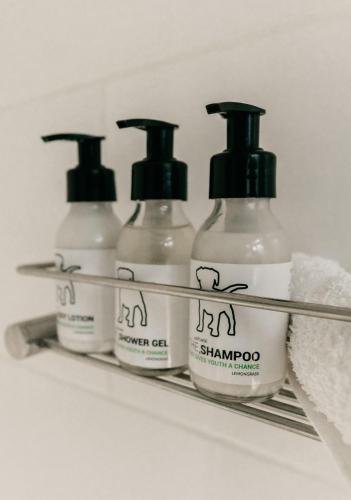 a group of four shampoo bottles on a shelf at theLAB Luxury Backpackers in Franschhoek