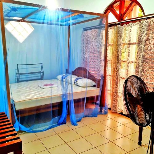 a bedroom with a canopy bed with a fan at Stylish Escape House-Walk to Beach Vacation Rental Hikkaduwa in Hikkaduwa