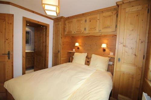 a bedroom with a large white bed with wooden walls at Gai Torrent 103 in Bagnes