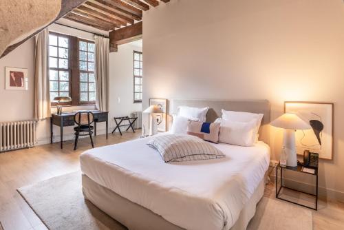 a bedroom with a large white bed and a desk at Les Manoirs des Portes de Deauville - Small Luxury Hotel Of The World in Deauville
