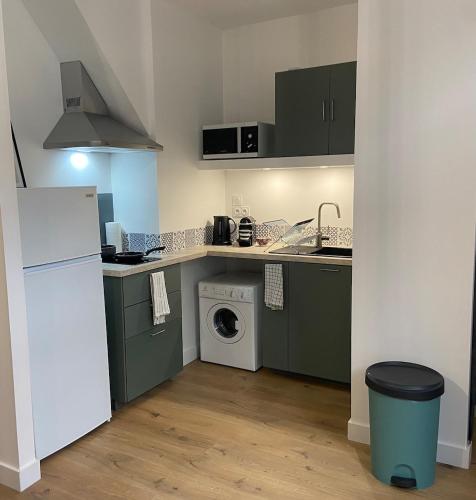 une cuisine avec des armoires vertes et une machine à laver dans l'établissement Appartement neuf, plein centre Latresne-Gironde, à Latresne