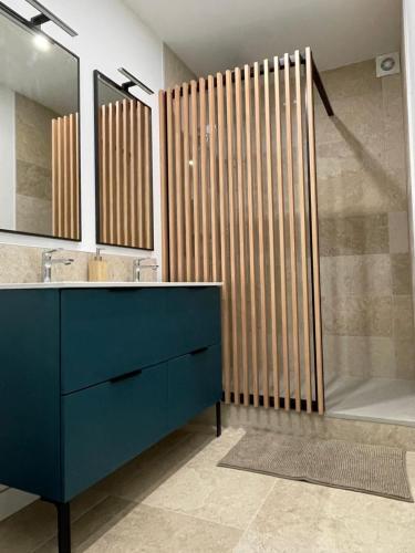 La salle de bains est pourvue d'une coiffeuse bleue et d'une douche. dans l'établissement Appartement neuf, plein centre Latresne-Gironde, à Latresne