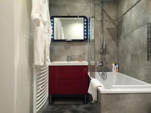 une salle de bain avec une baignoire, un lavabo et un miroir dans l'établissement UnSejourAMetz - Gite Metz Chapelle, 3 chambres & Garage, à Metz