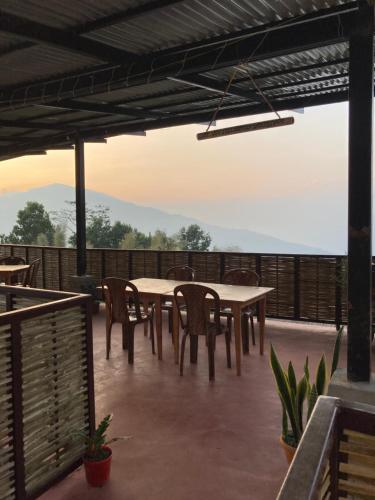 a patio with tables and chairs on a deck at Art Mile Kalimpong in Kalimpong