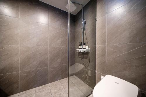 a bathroom with a glass shower with a toilet at The Western Busan Hotel By STAYNEO in Busan